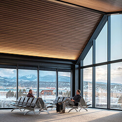 A couple of people sitting in chairs in front of a building with large windows.